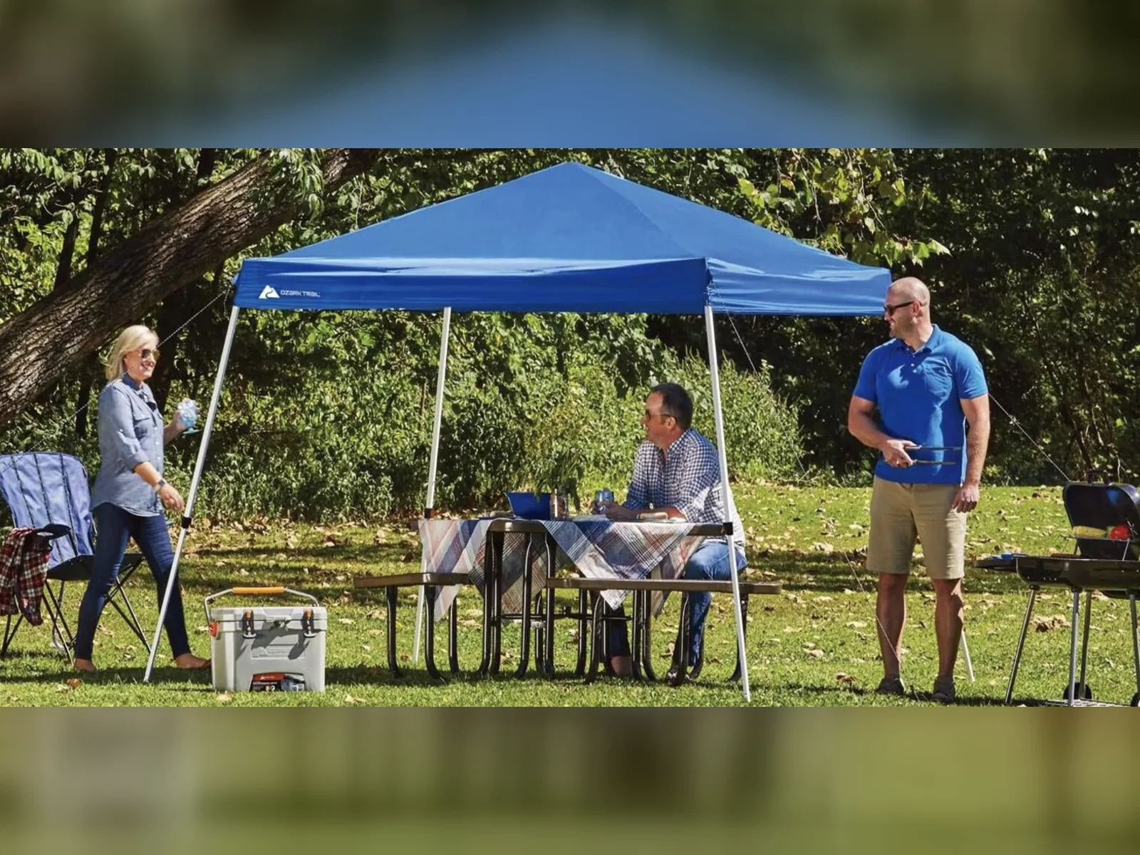 Blue 10x10 slant-leg pop-up canopy shading a picnic table on a lawn